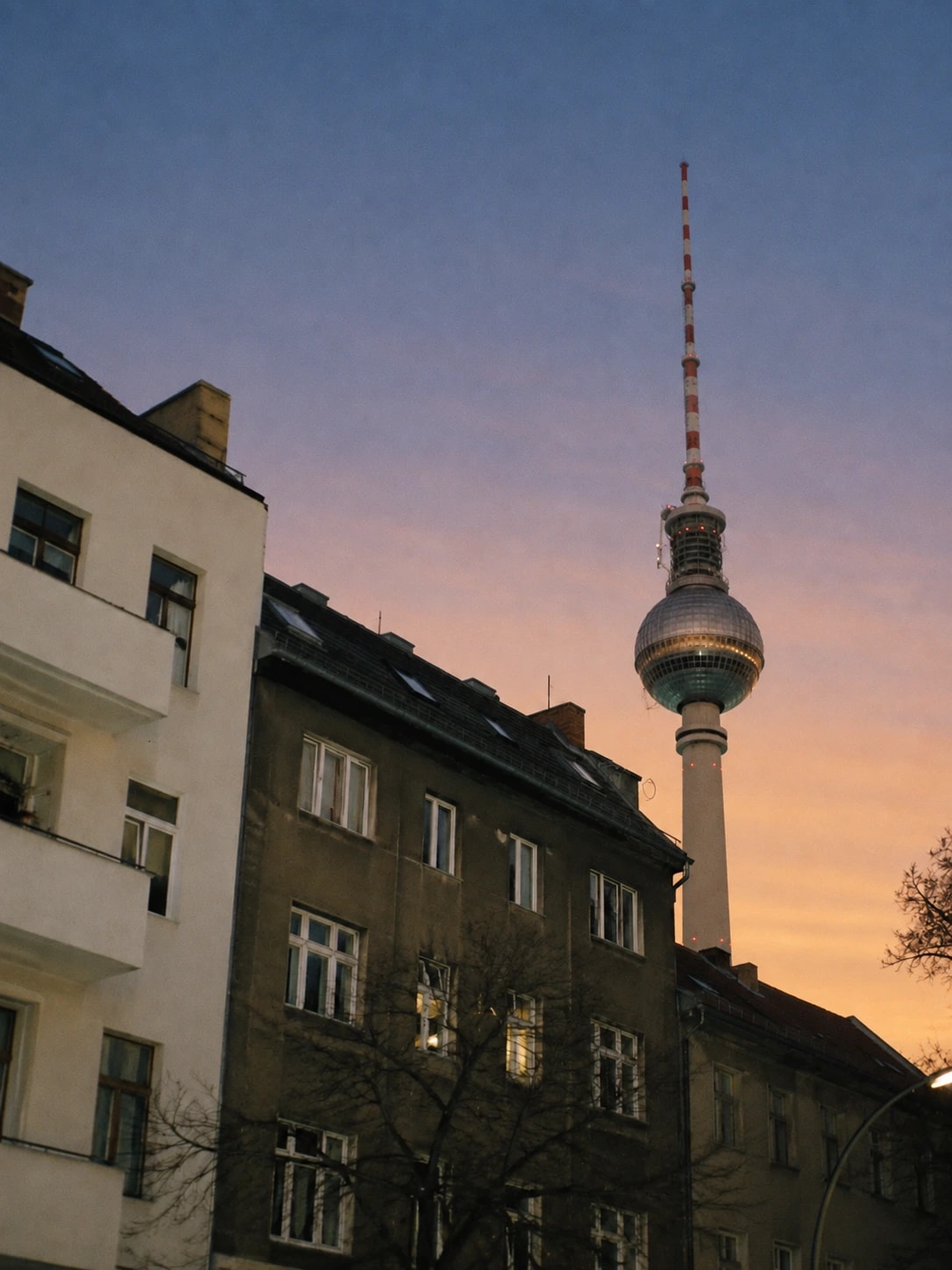 Berlin TV Tower rising above apartment buildings at dusk